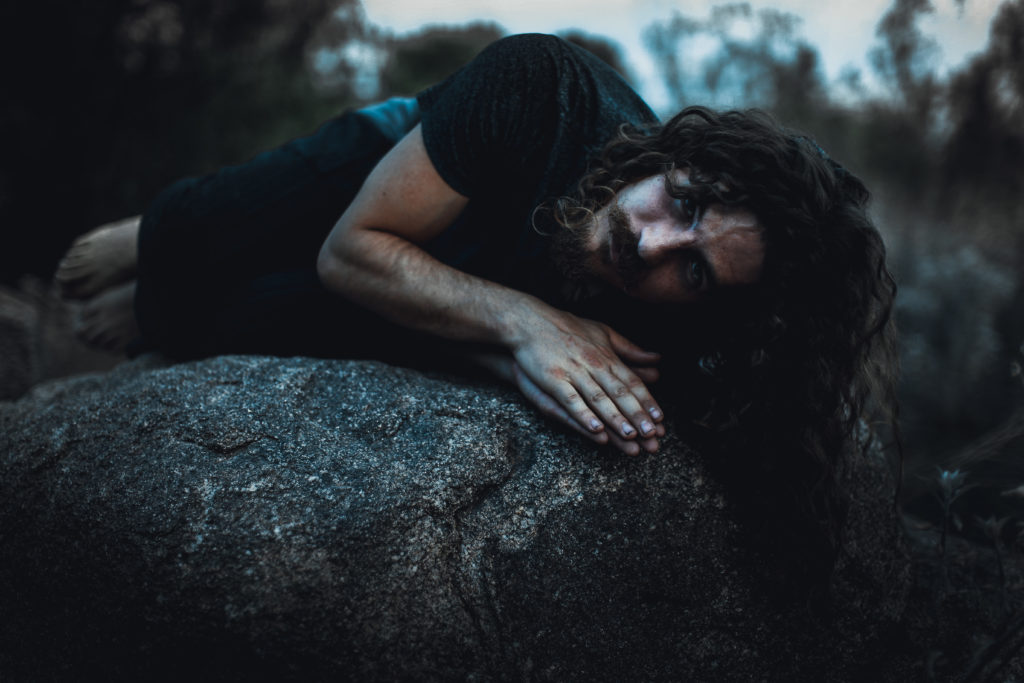 man appears homeless, laying on rock at night